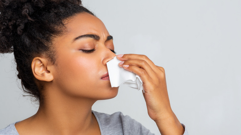 Woman holding tissue to bloody nose 