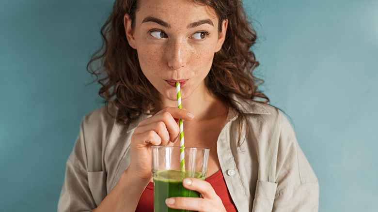 woman drinking a green smoothie