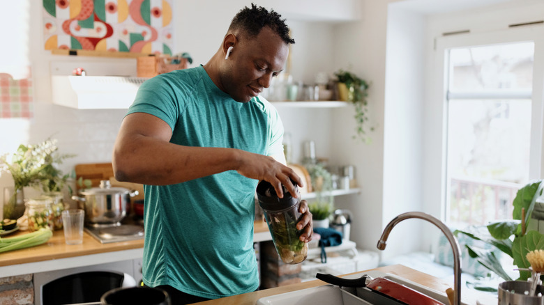 man in workout clothes making a smoothie