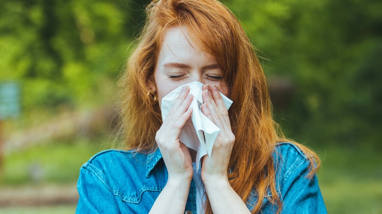 woman holding tissue to nose