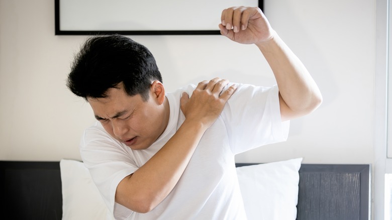 man sitting in his bed with shoulder pain