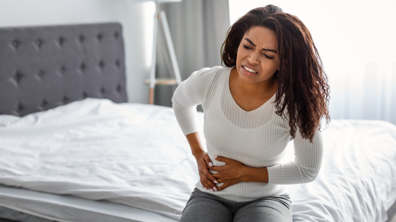 Grimacing woman holding her stomach