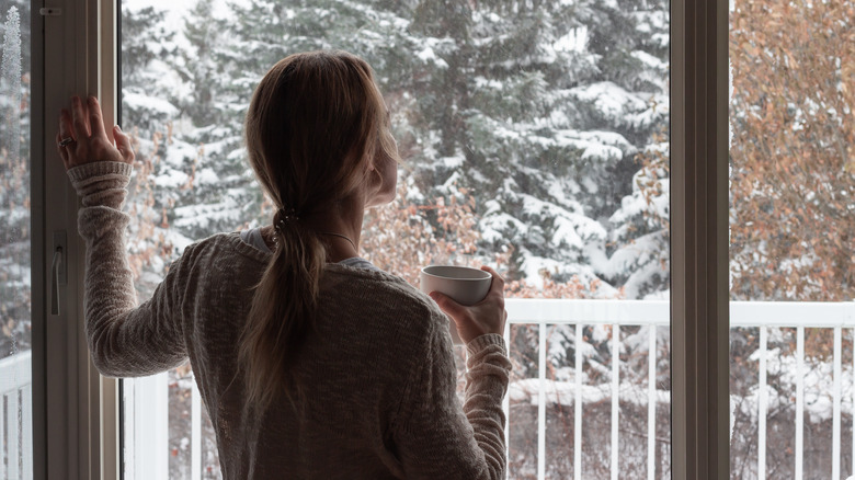 woman looking out of snowy window
