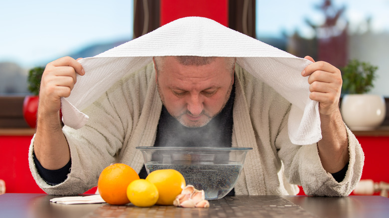 man leaving face over steaming water bowl