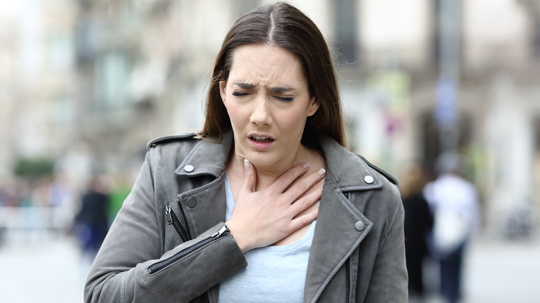 woman wheezing while walking on city street