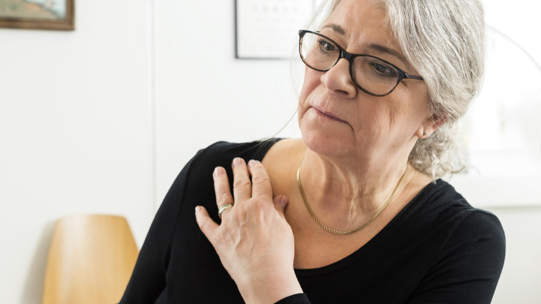 A woman touching her shoulder