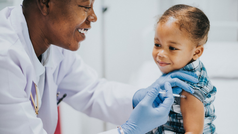 Young smiling child receiving vaccine from smiling doctor