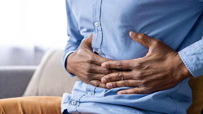 A man's hands holding his stomach in pain