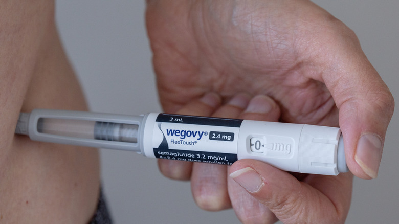 A 2.4-milligram Wegovy injector pen going into a person's side
