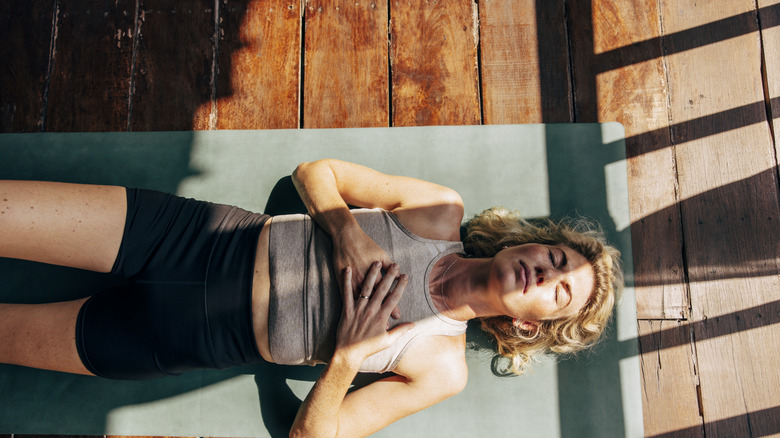 Woman lying on exercise mat on floor