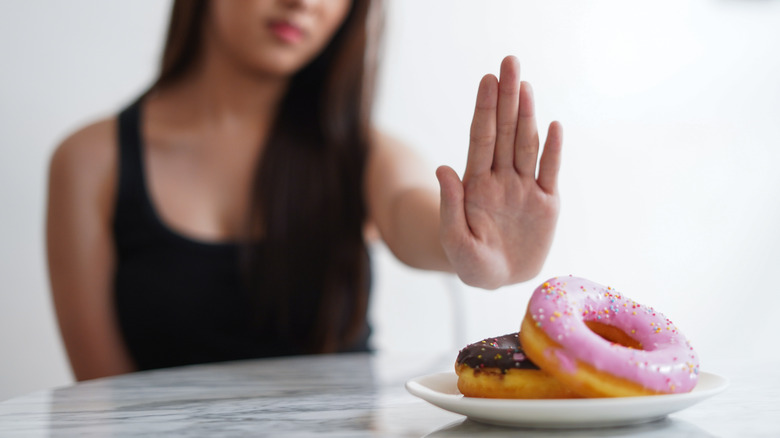 Woman rejecting a plate with two donuts on it