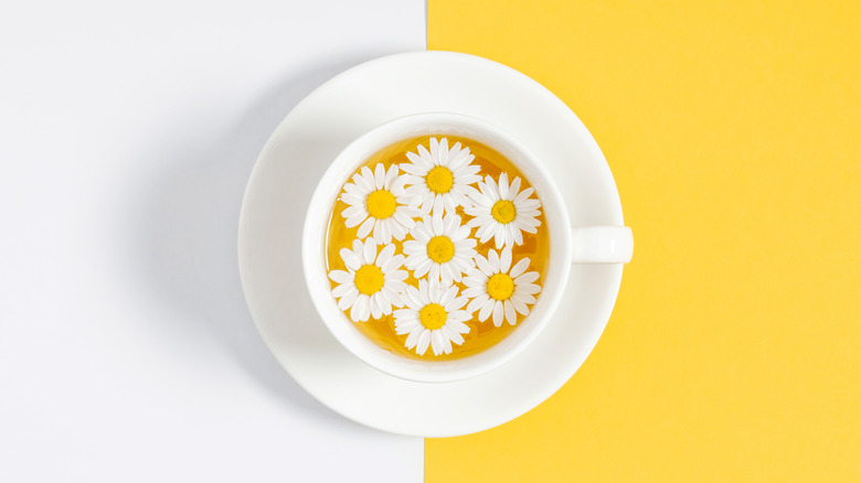 Cup of chamomile tea with flowers floating in it 