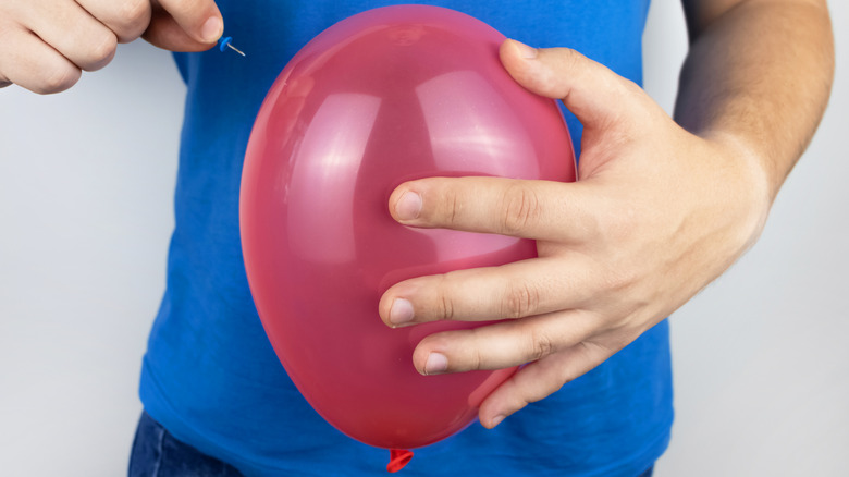 person about to pop balloon