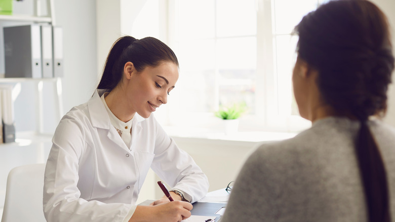 Woman in white coat consulting patient from a desk