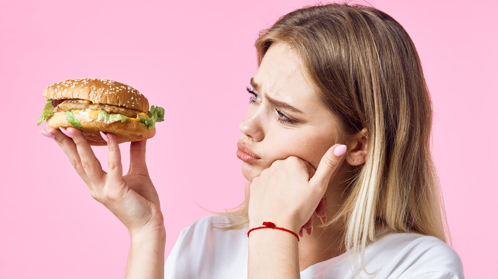 sad woman holding fast food sandwich
