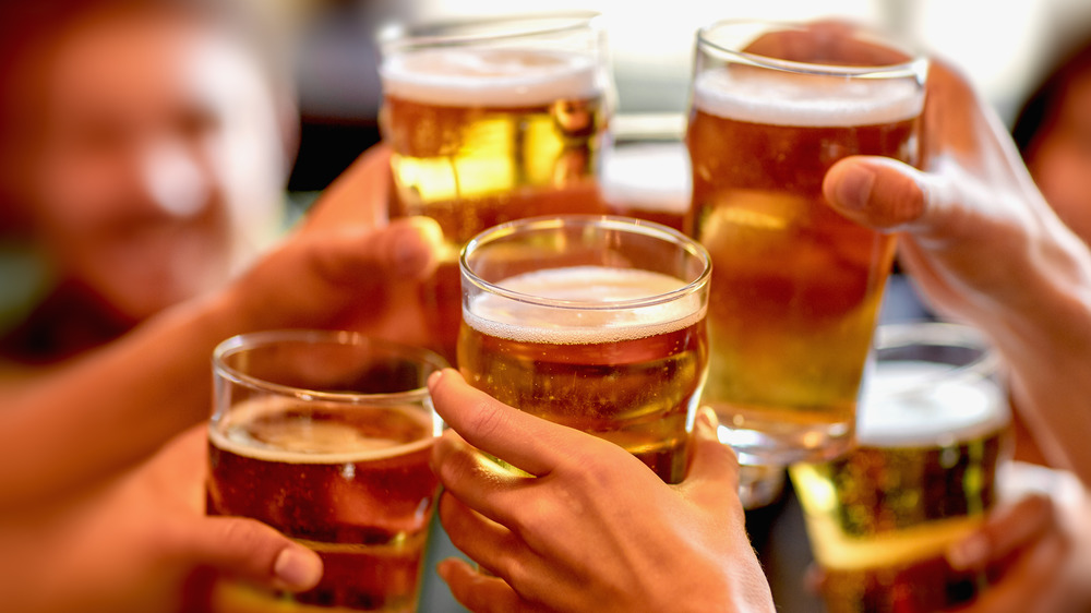 Five hands holding full beer glasses