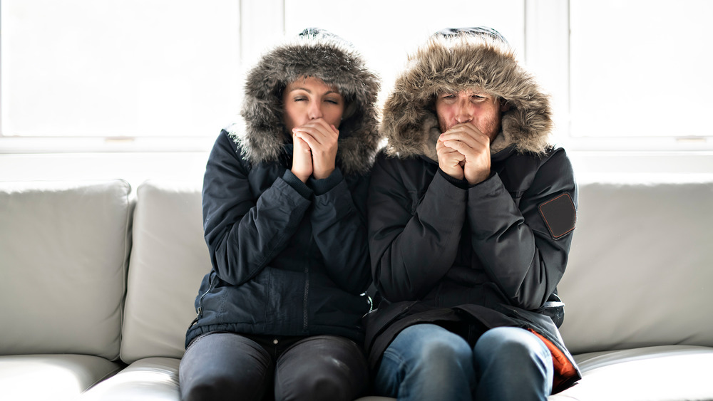 Couple sitting on couch in winter coats