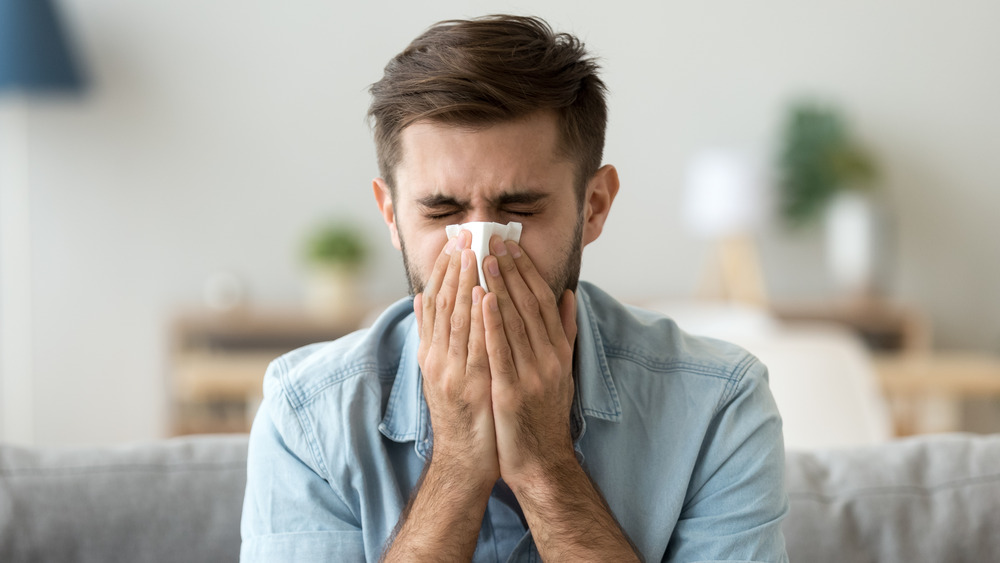 Man blowing nose with tissue