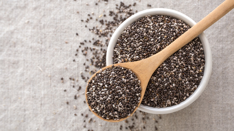 A bowl of chia seeds with a wooden spoon on top