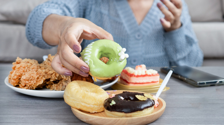A woman's hand reaching for a plate of donuts