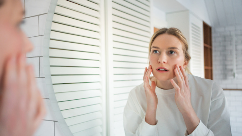 A woman looking at her face in the mirror
