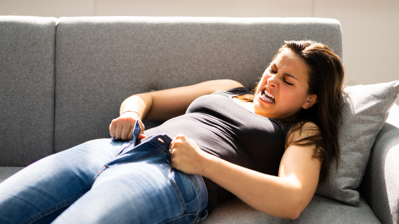 Woman struggling to zip up her jeans