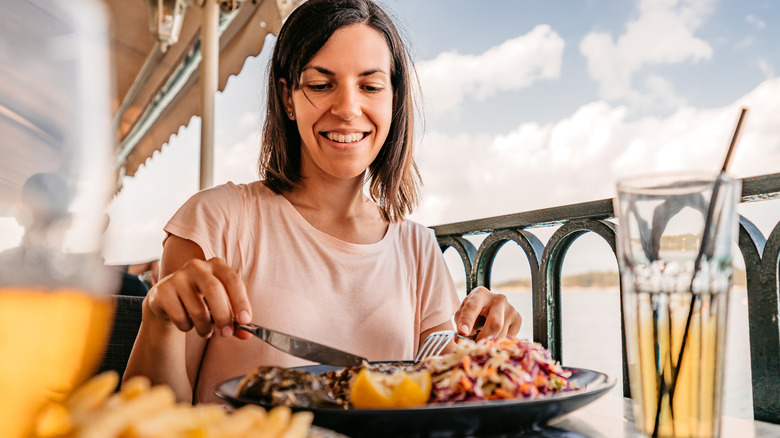 woman eating a seafood meal by the water
