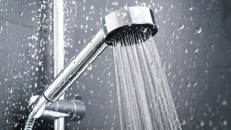 Fresh shower behind wet glass window with water drops splashing