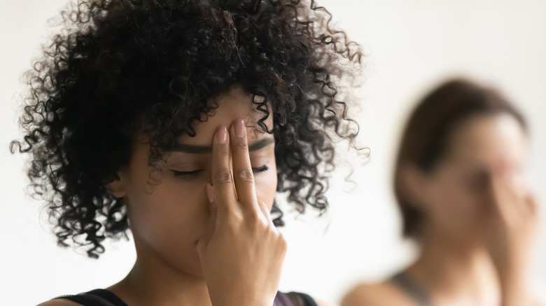 Two women in yoga class engaged in alternate nostril breathing