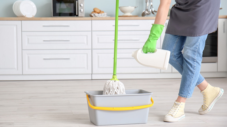 person pouring cleaning product in bucket