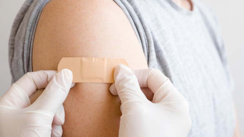 Gloved hands applying a bandage to a man's arm