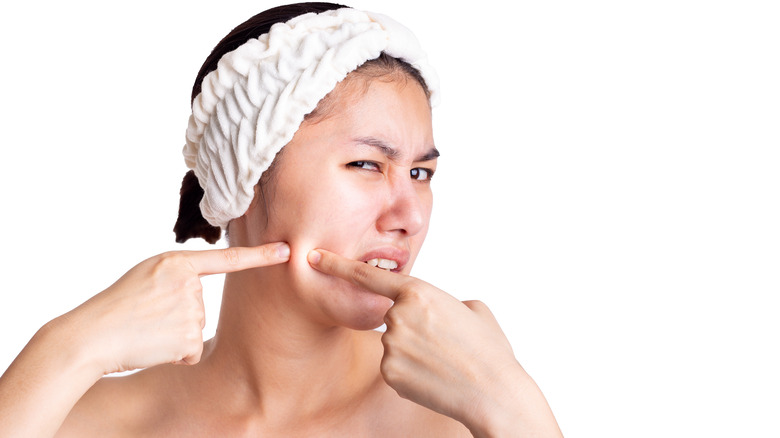 Young woman popping skin on face
