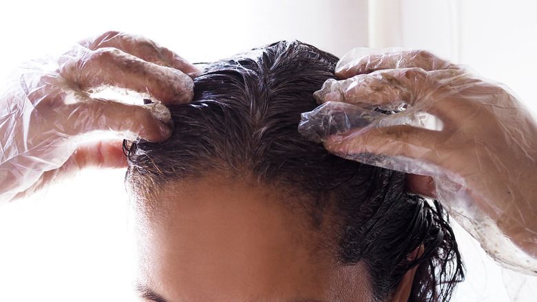 woman wearing protective gloves while applying hair dye