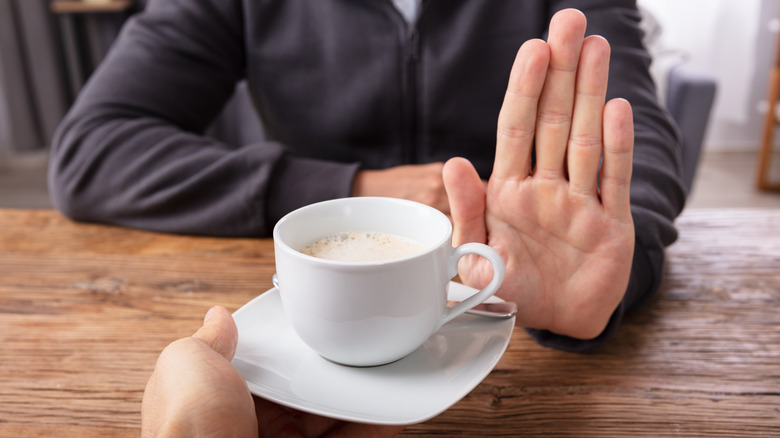 Close-up of a man's hand refusing cup of coffee 