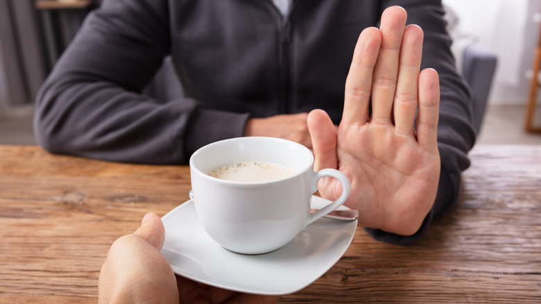 Close-up of a man's hand refusing cup of coffee