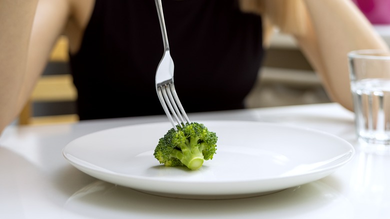 A picky woman eats broccoli
