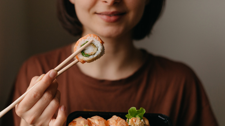 Woman holding sushi with chopsticks