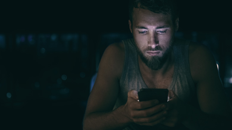 Man staring at his phone late at night instead of sleeping