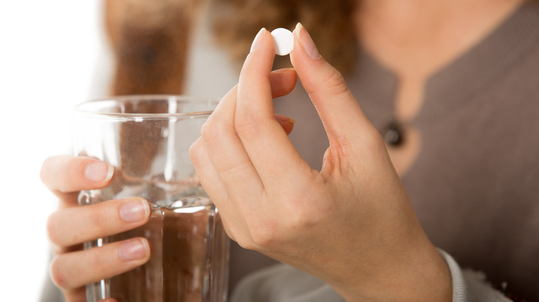 Hands holding a sleeping pill and glass of water