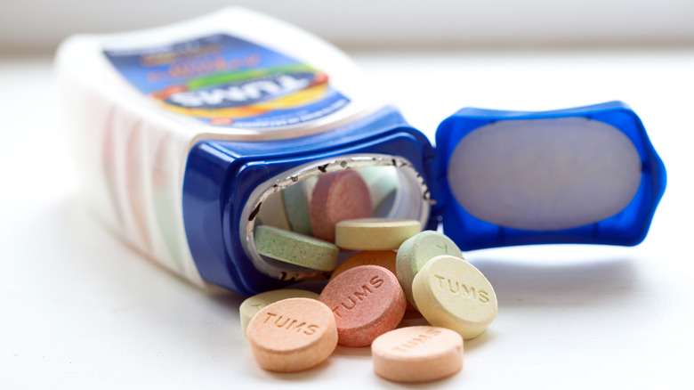 Bottle of TUMS lying down on a white table with several pills spilling out