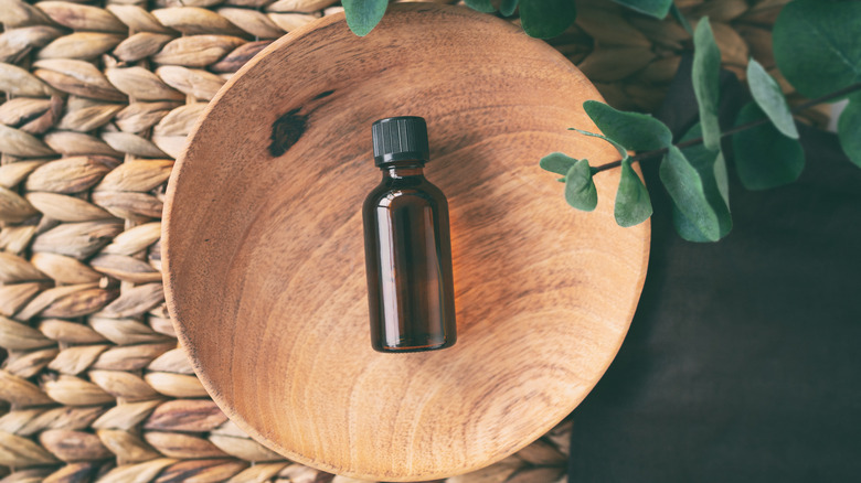 A bottle of essential oil in a wooden bowl