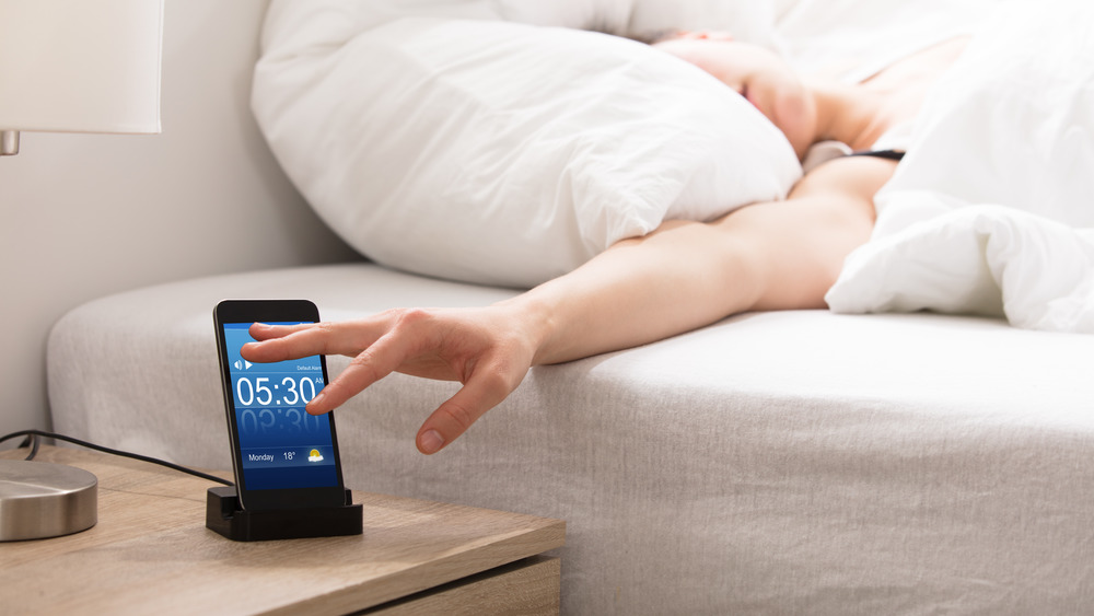 Woman Sleeping On Bed Snoozing Alarm On Smart Phone Screen