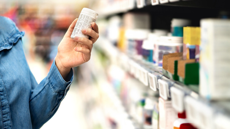 Customer in pharmacy holding medicine bottle