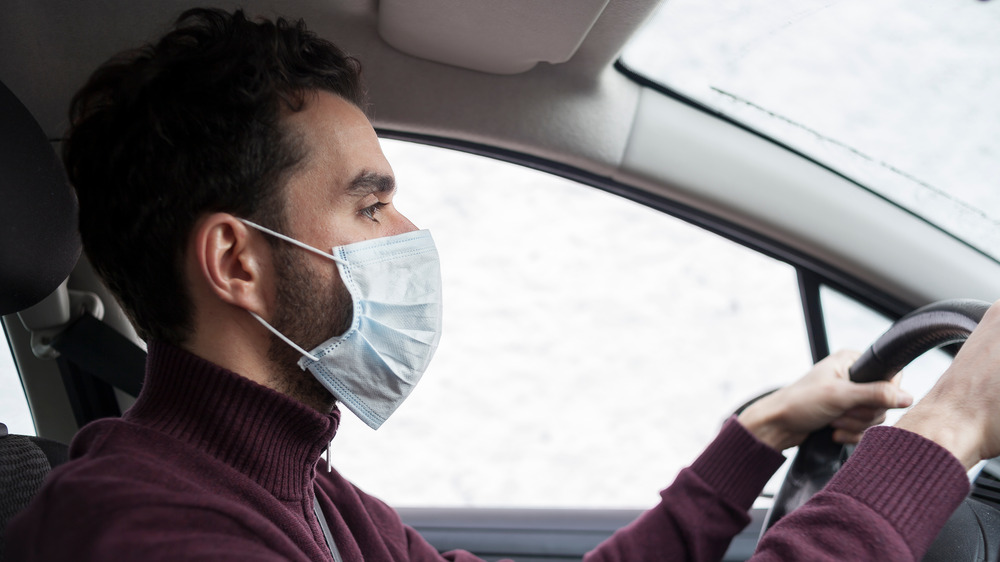 Man with beard driving with mask on