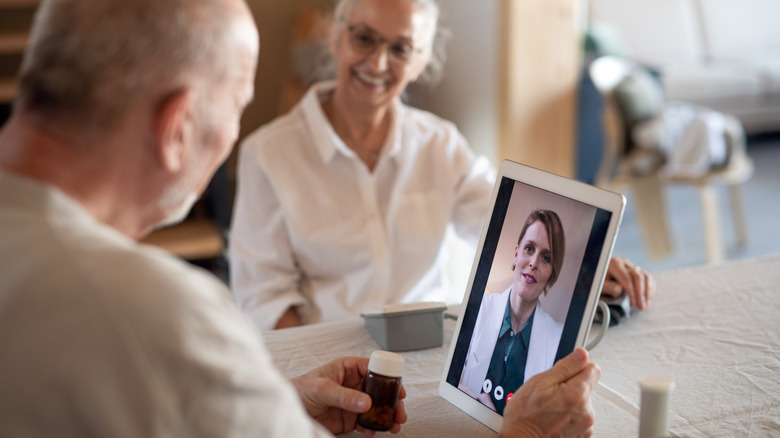 man talking with doctor on tablet with woman at his side