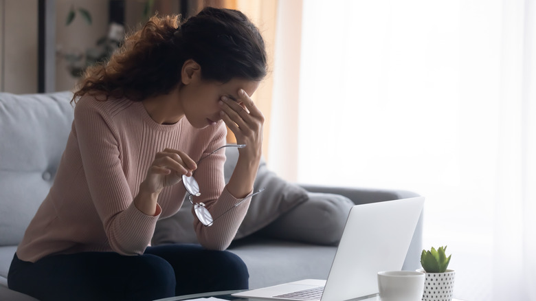 Woman rubbing her eyes while using the laptop