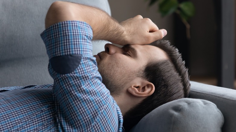 Tired and dizzy man lying on sofa