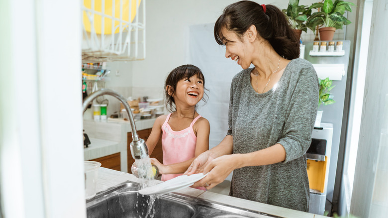 mom and daughter washing dishes in the sink