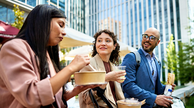 two women and man eating in a park