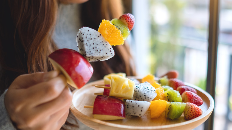 woman eating fruit on skewer